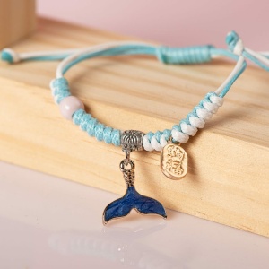 Bracelet tressé avec pendentif animaux de mer en bleu et blanc , sur une etagere en bois