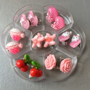 Ensemble de 7 boucles d'oreilles à clip pour enfant en rose, dans une divisoire transparente avec fond blanc