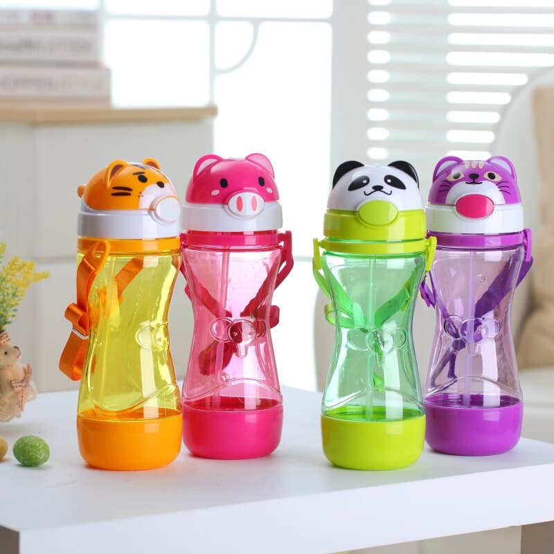 Gourde enfant 450 ml en forme animal 3D colorés sur une table, devant une fenetre