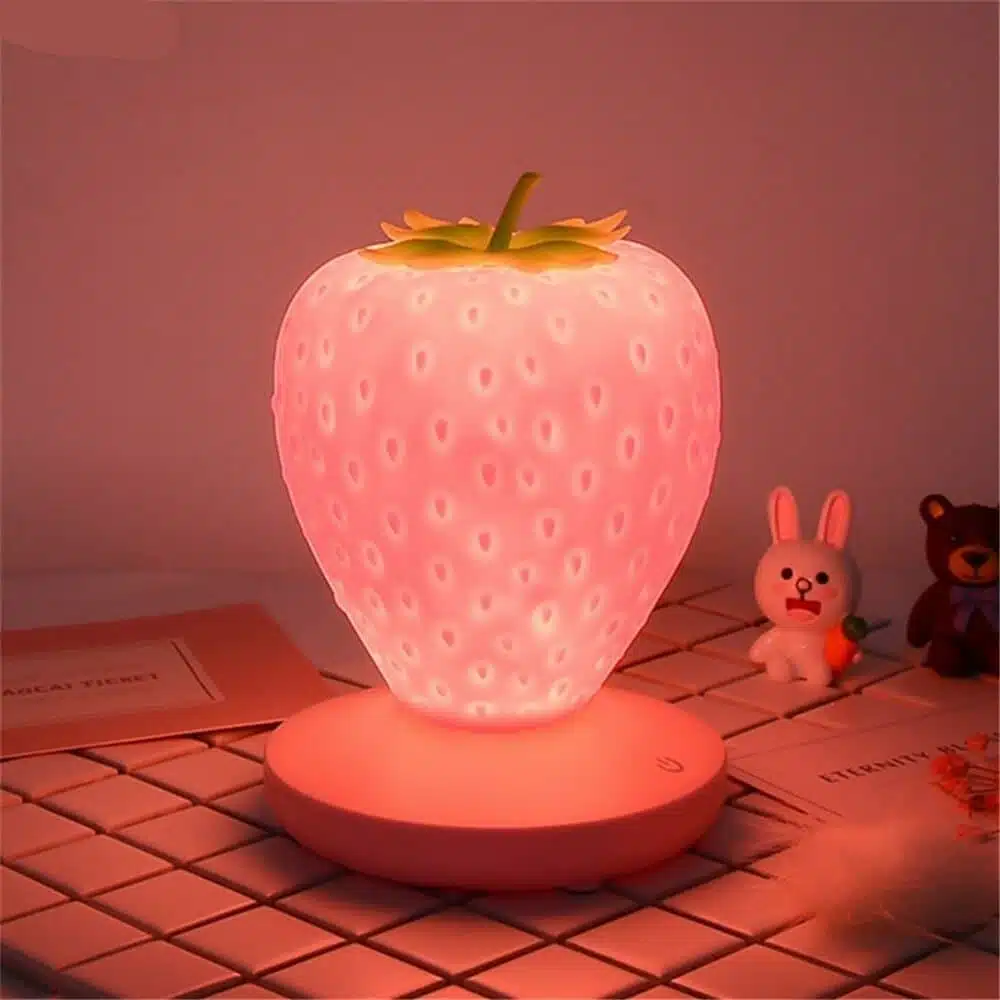 Lampe de chevet enfant en forme de fraise. Bonne qualité et très tendance sur une table dans une maison.