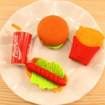 3 pièces de gommes en forme de nourritures pour enfant dans une assiétte blanche sur une table en bois