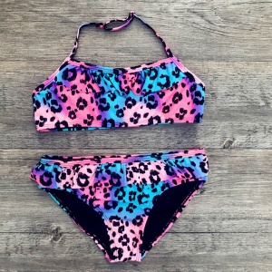 Maillot de bain 2 pièces imprimé léopard pour fille coloré rose, violet et bleu sur du bois gris