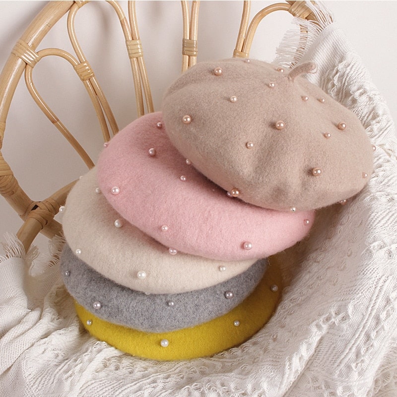 Béret de princesse à perles pour enfant sur une chaise en rotin avec couverture en blanc