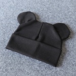 Bonnet en coton avec petites oreilles pour bébé en noir sur fond gris