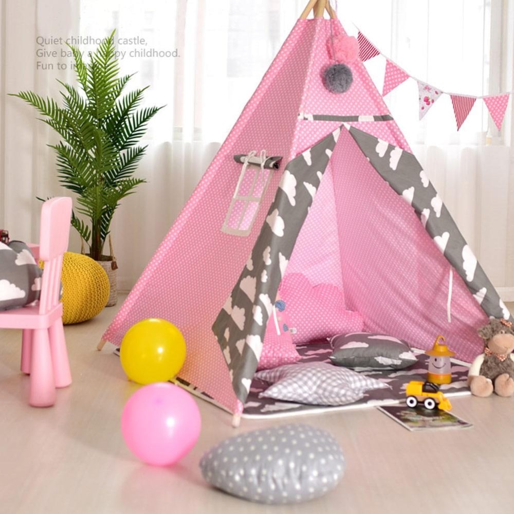 Tipi petit points blanc et rose pour enfant dans une chambre avec une plante verte et des ballons par terre, avec une chaise rose