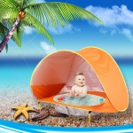 Tipi de plage pour enfants orange, avec bebe a l'interieur dans une plage avec la mer et un palmier