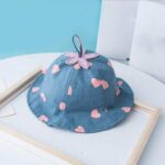 Chapeau d'été en dentelle pour enfants bleu avec fleurs en rose sur une table blanche