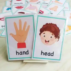 Jeu de cartes pour bébé avec main et tete et d'autres cartes sur un lit