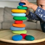 jouets empilables en pierre colorée pour enfants sur un plat en bois