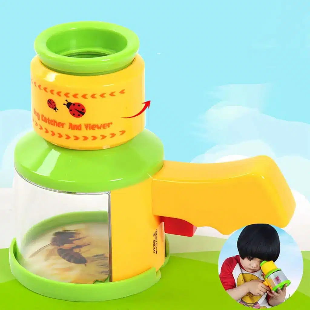 Un jeune garçon aux cheveux noirs qui joue avec un microscope en jouet jaune et vert