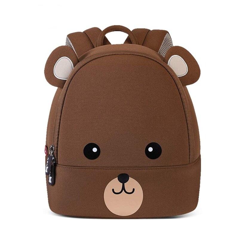 Un sac à dos pour enfant marron en forme d'ours avec des yeux une bouche et des oreilles qui dépassent du sac