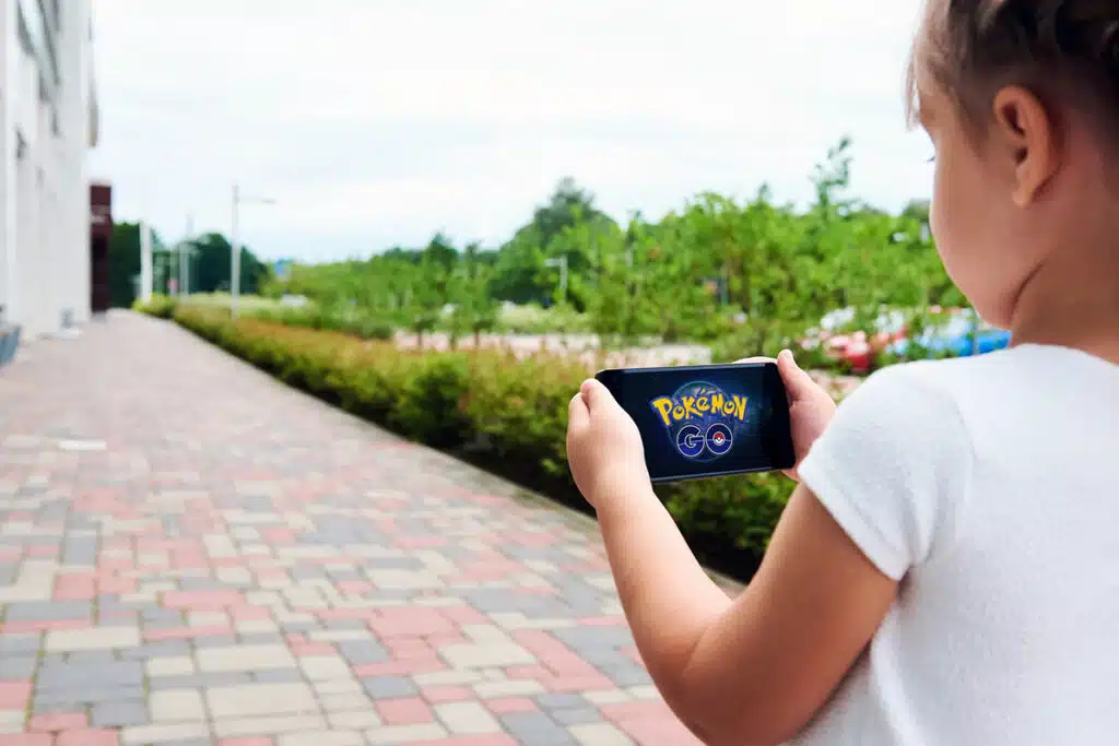 Une jeune fille qui marche dans la rue en jouant à pokemon go sur son smartphone. 