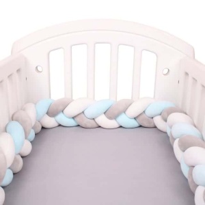Tour de lit tressé blanc gris bleu dans un lit de bébé blanc avec draps en gris