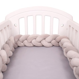 Tour de lit tressé gris dans un lit de bébé blanc et draps en gris