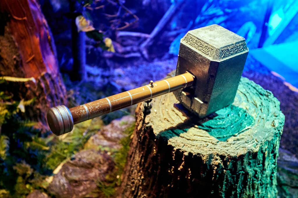 Un marteau de Thor posé sur une souche d'arbre dans une forêt la nuit.