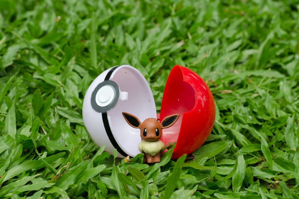 Une statuette du pokemon evoli devant une pokeball dans de l'herbe verte
