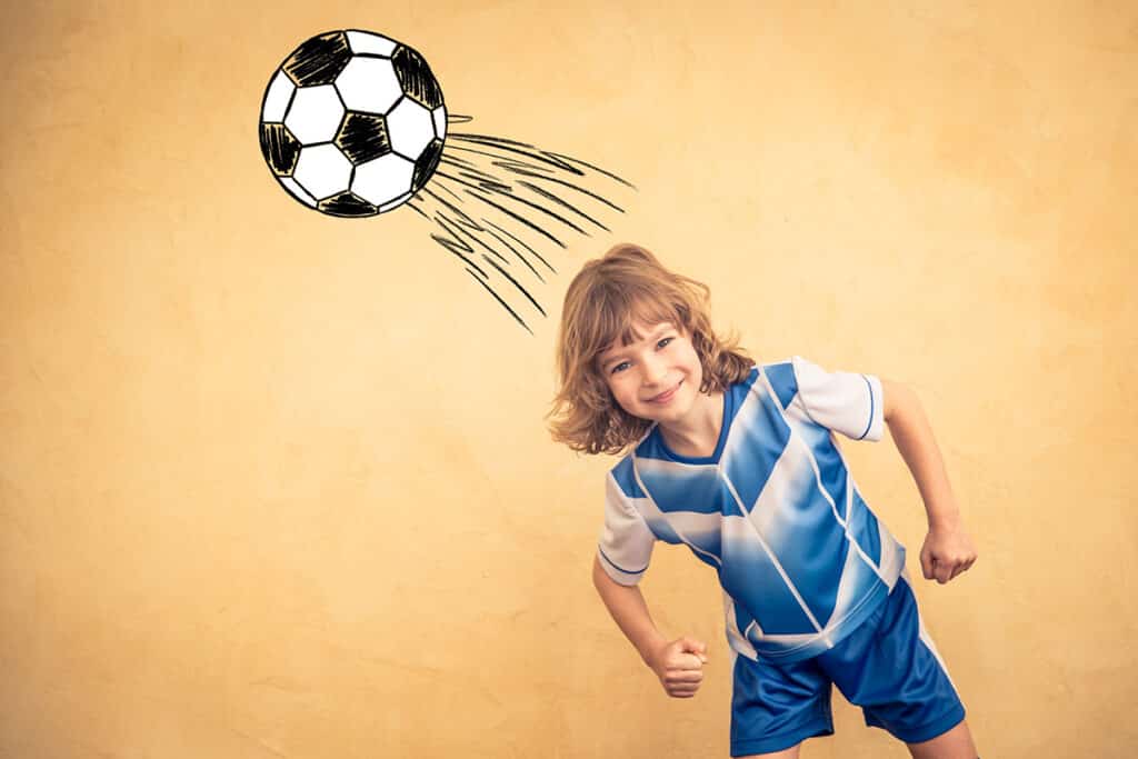 un jeune garçon en tenue de football bleu qui joue avec un ballon de foot