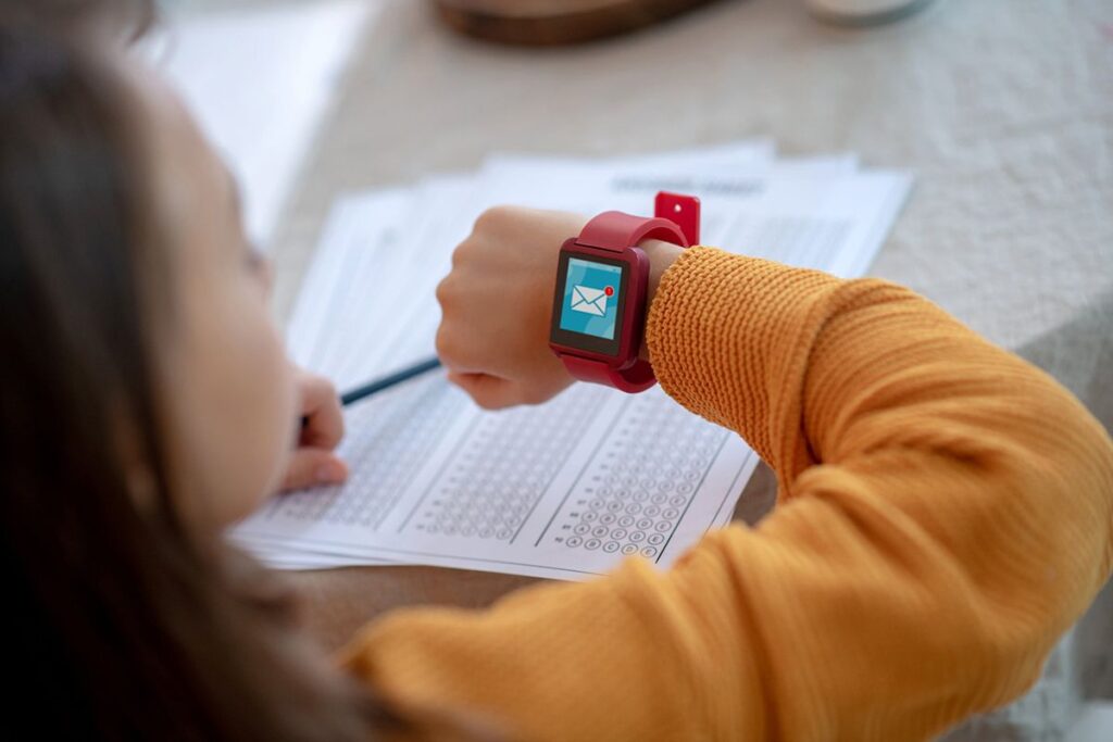 Une jeune fille à l'école qui regarde sa smartwatch. Il y a une alerte message sur le cadran de la montre.