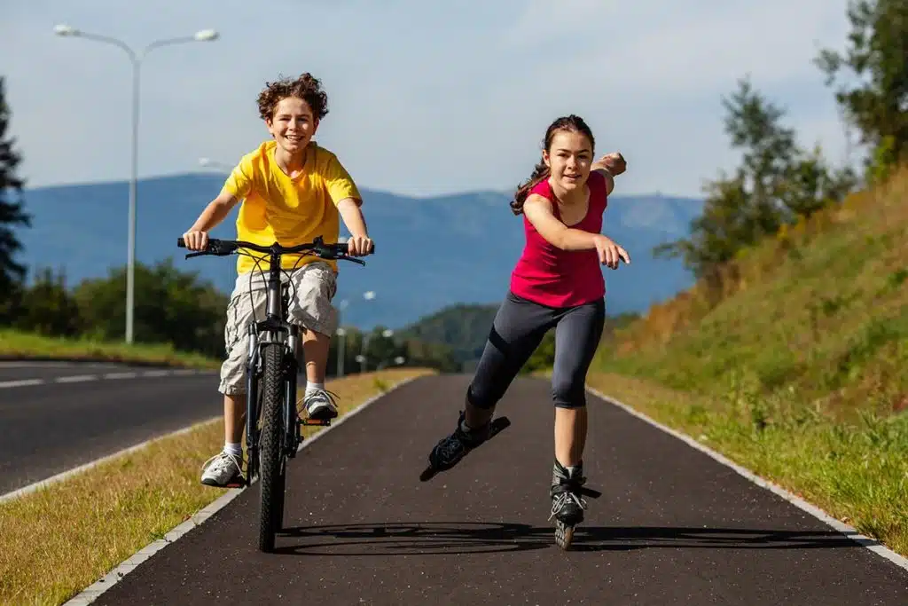 Deux jeunes adolescents qui font du roller et du vélo. Les jeunes ne portent pas de casque de protection.