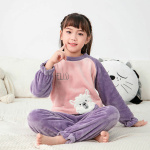 Pyjama polaire en flanelle avec un motif mignon pour enfants en violet et rose sur une fille dans un tapis blanc avec un coussin derriere