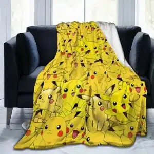 Plaid Pokémon à motif Pikachu pour enfants sur un canapé noir devant une fenetre