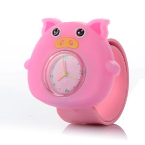 Une montre pour enfant en forme de cochon rose mignon. En son centre elle a un cadran en verre avec des aiguilles et des chiffres colorés.