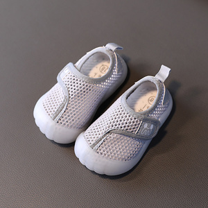 Chaussure de plage pour enfant en maille grise avec une semelle en caoutchouc blanc. Elles sont posées sur un fond gris foncé.