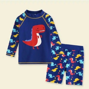 un ensemble de maillot de bain pour enfant short et tee-shirt bleu avec motif dinosaure posé sur un fond beige