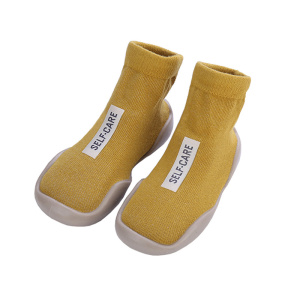 paire de chausson-chaussettes jaune avec un étiquette blanche sur le dessus, présenté sur fond blanc