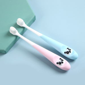 2 brosses à dents pour bébé de couleurs rose et bleu posées à plat sur un support vert