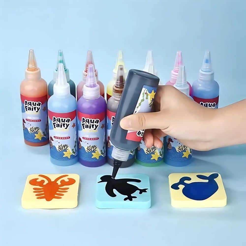 Peinture magique à l'eau auto-durcissante sur fond bleu. On voit la main d'une personne en train de créer un petit animal avec cette peinture, dans un moule en forme de pingouin. On aperçoit deux autres moules remplis, en forme de langouste et de baleine.