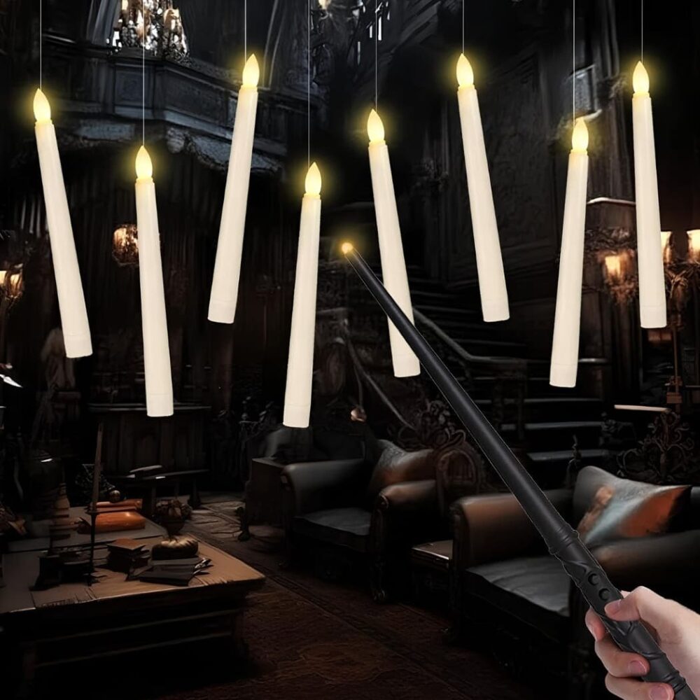 Bougies flottantes LED Harry Potter avec baguette magique. Les bougies longues blanches et fines sont suspendues par un fil transparent. Au bout une lumière LED allumée. En fond, un décor dans l'obscurité avec des fauteuils, une table basse et des lanternes. En premier plan, une main tenant une baguette en direction des bougies.