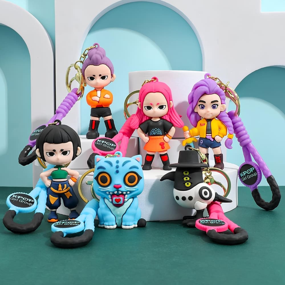 IMG_10_2025_lot_de_6_porte_clés_K_pop_Demon_Hunters_2 Lot de 6 porte-clés K-pop Demon Hunters représentant les personnages du film, la pie et le tigre bleu. Posés sur des supports blancs. Le sol et le fond sont verts.